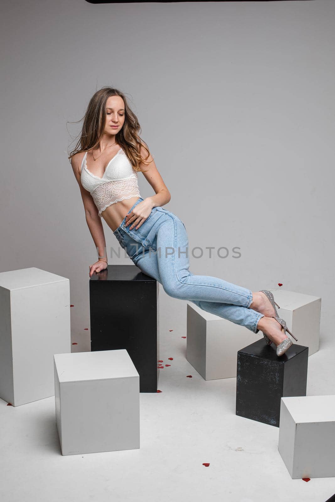 female model in white skirt and denim jeans poses for the camera on black and white cubes in the studio by StudioLucky