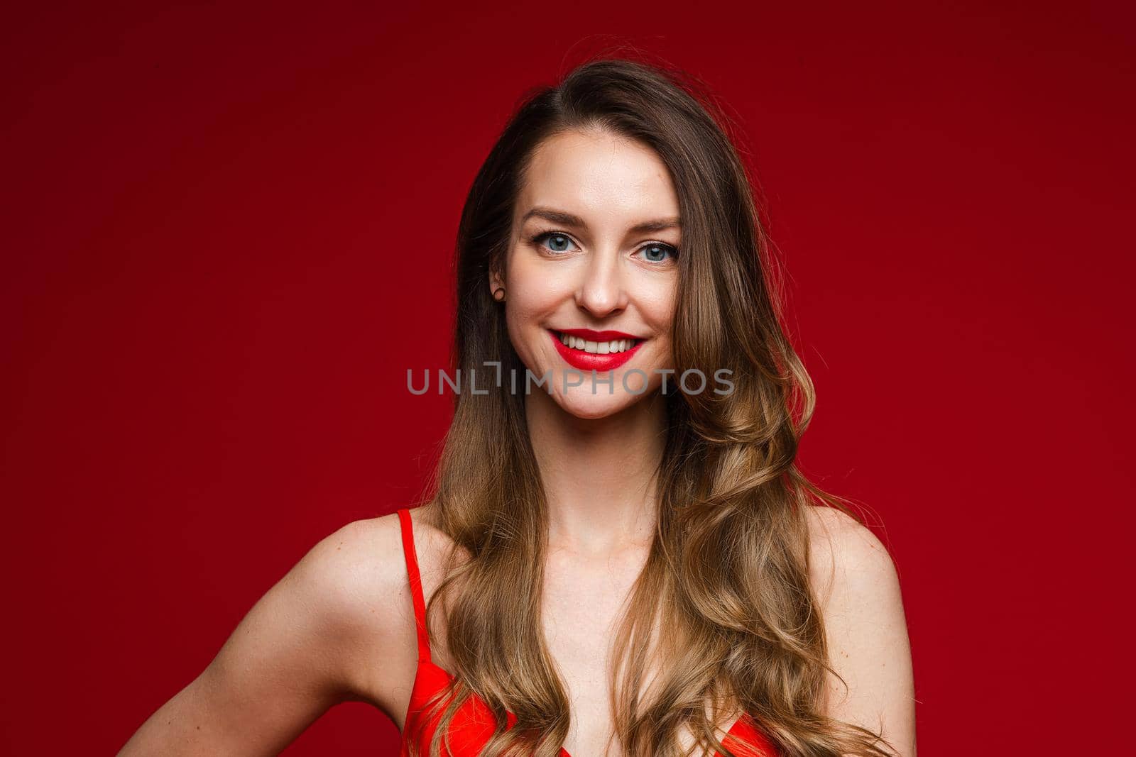 Portrait of happy pretty female wearing red dress while posing in studio. Saint Valentine Day concept