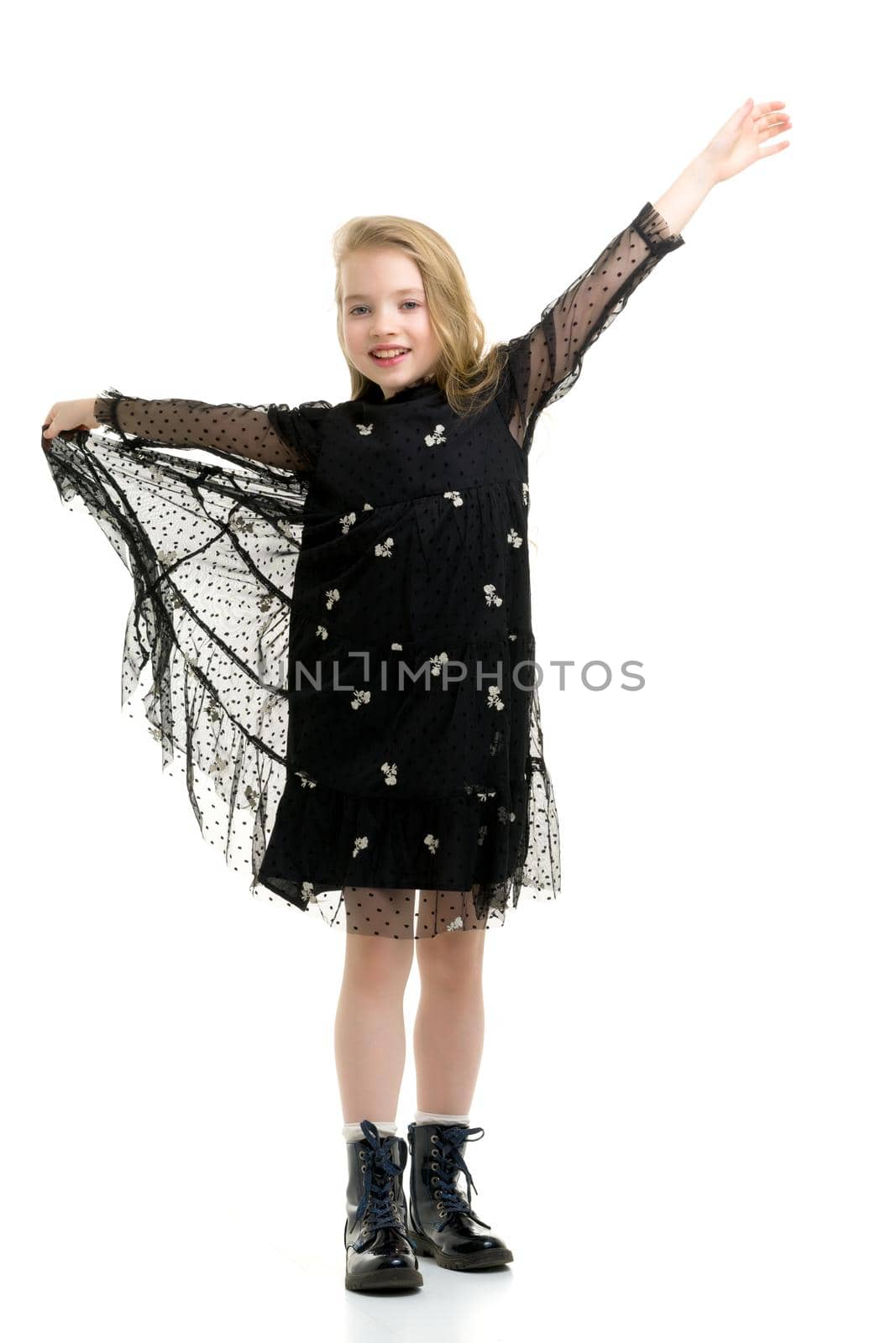 Beautiful little girl in an elegant dress holds her hands around the edges of the skirt. Isolated on white.