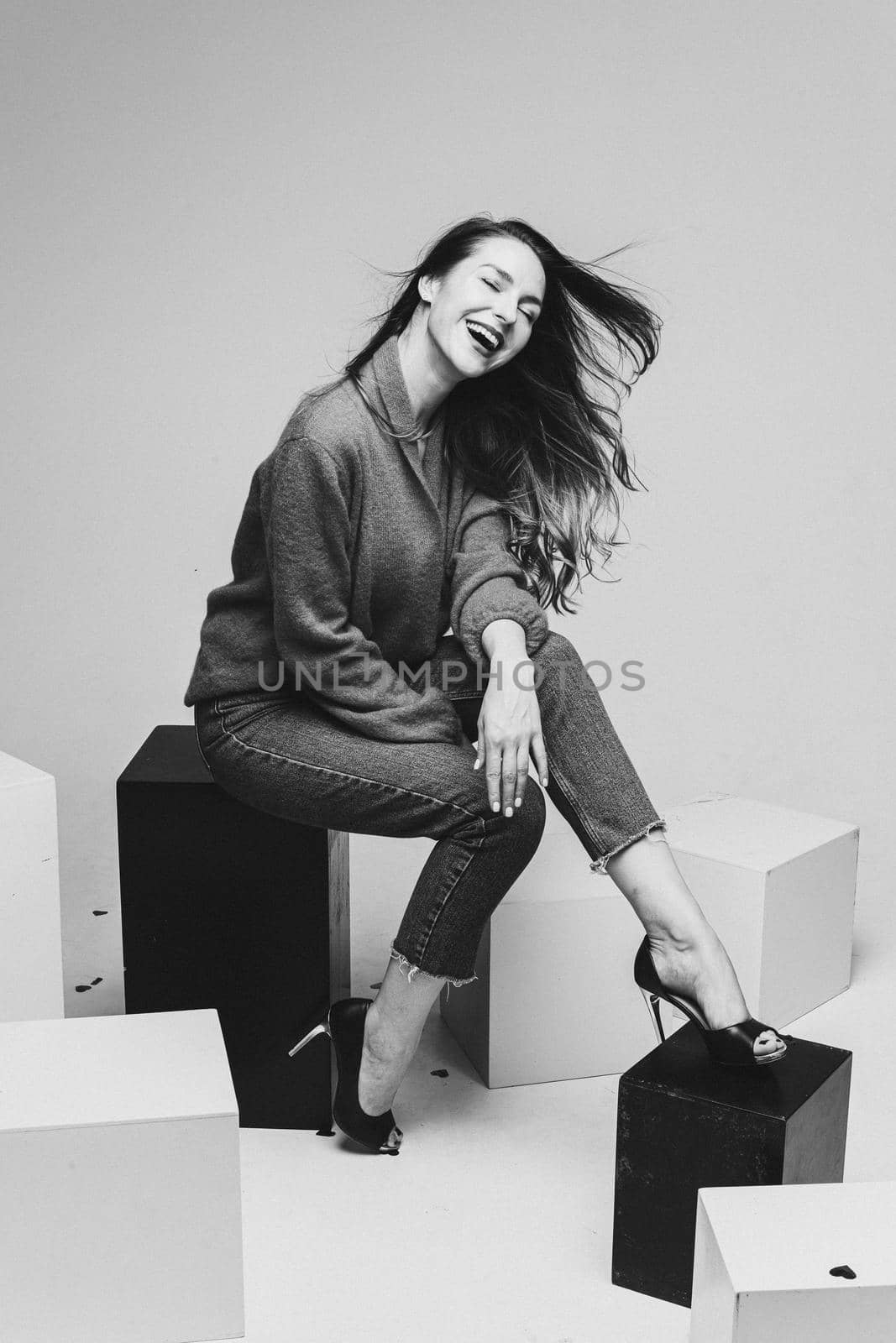 female model in black skirt and denim jeans poses for the camera on black and white cubes in the studio by StudioLucky