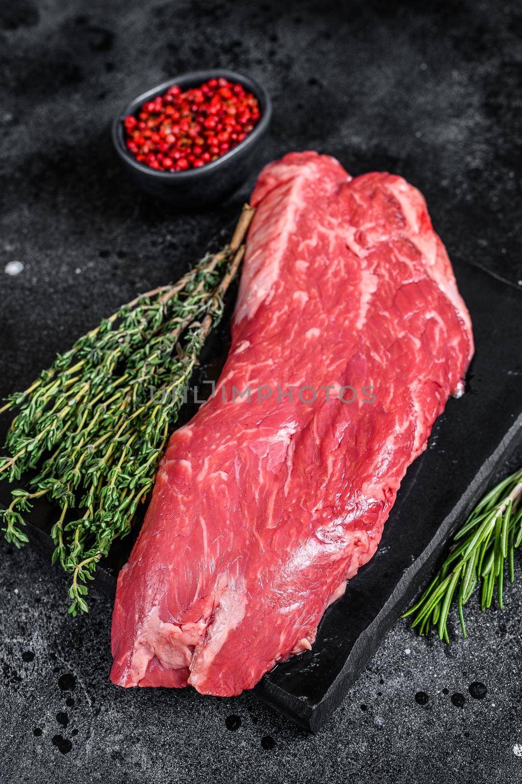 Raw flank beef meat steak. Black background. Top view.