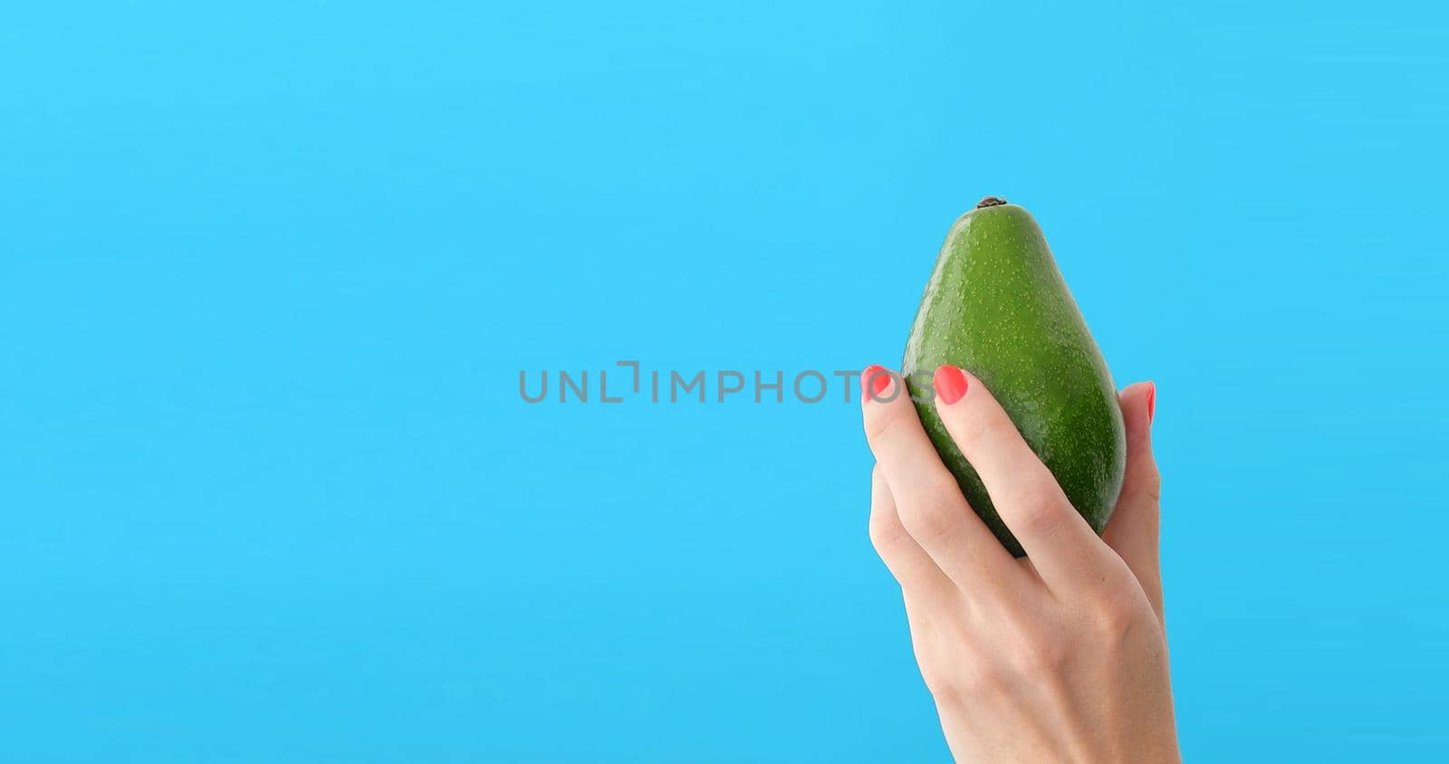 avocado in a hand of woman blue background by Demkat