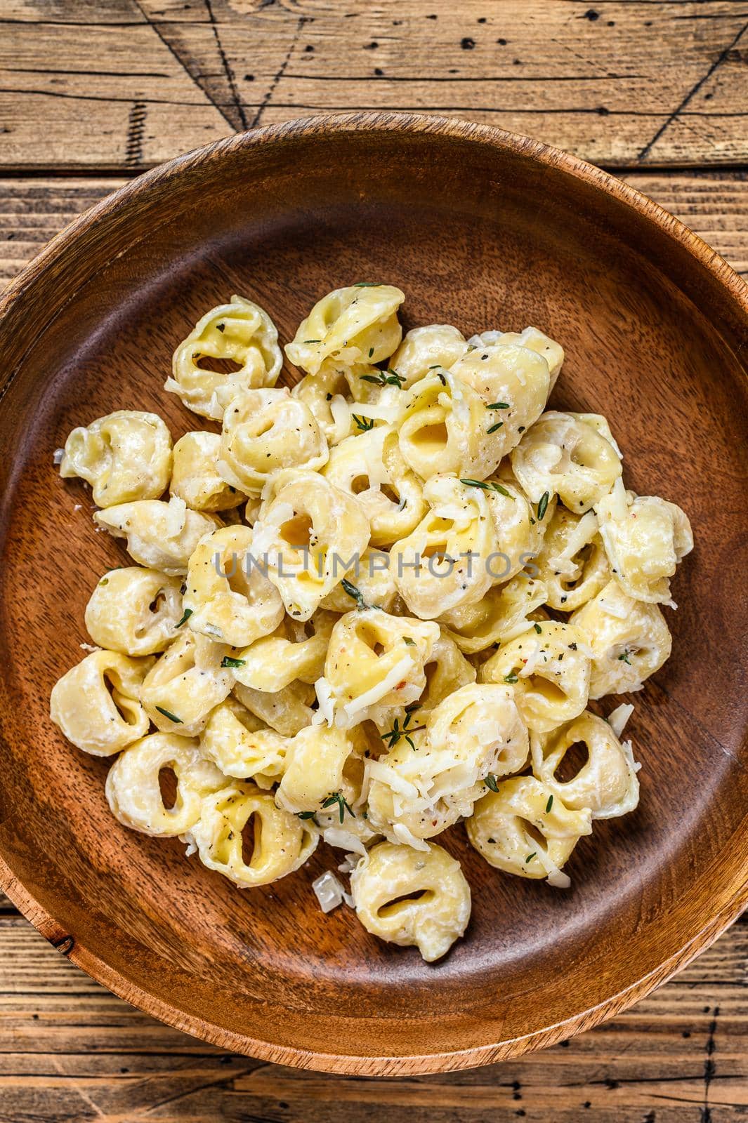 Ravioli or tortellini pasta in cream cheese sauce with meat. wooden background. Top view.