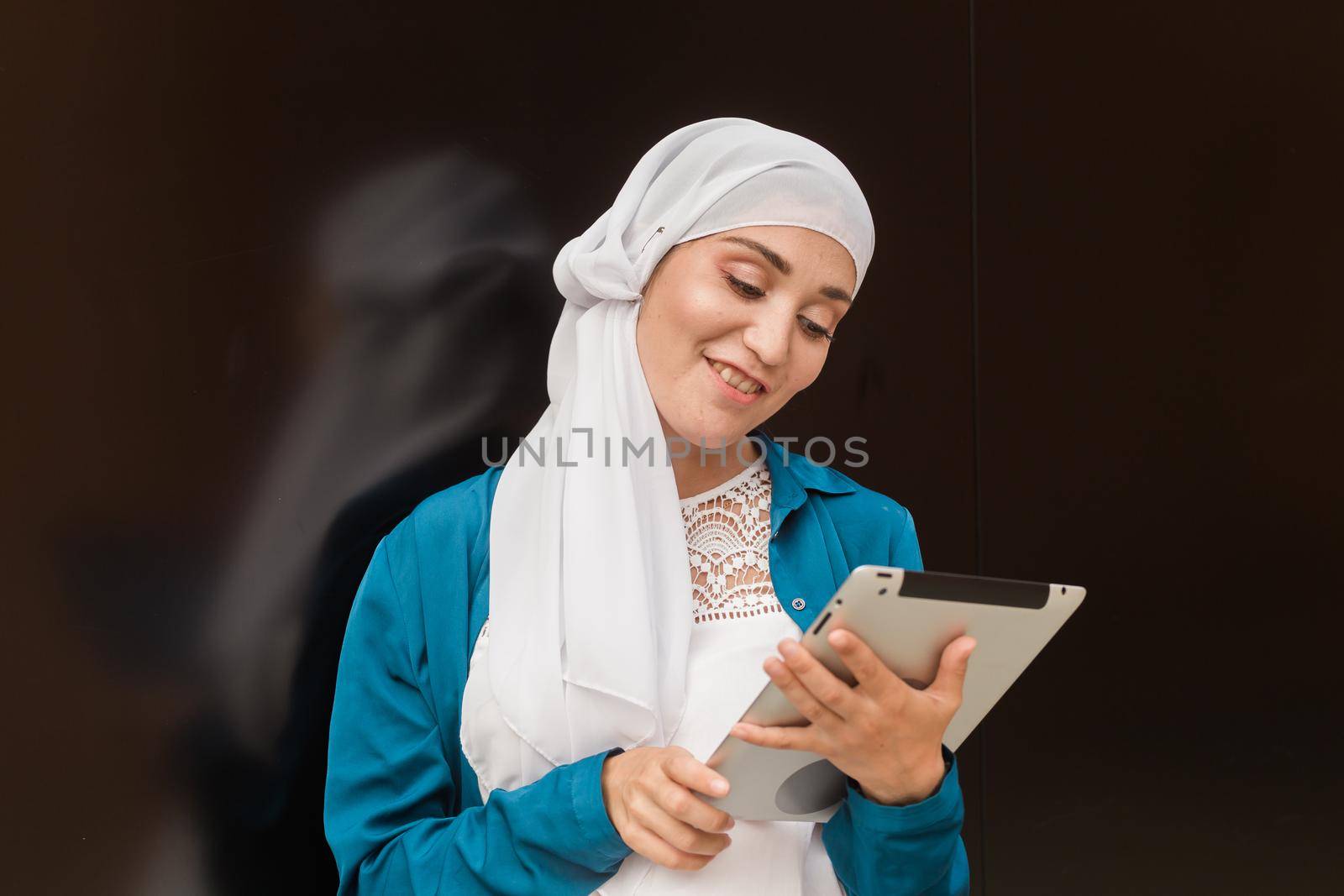 Beautiful muslim girl using digital tablet for communication with friend outdoor by Satura86
