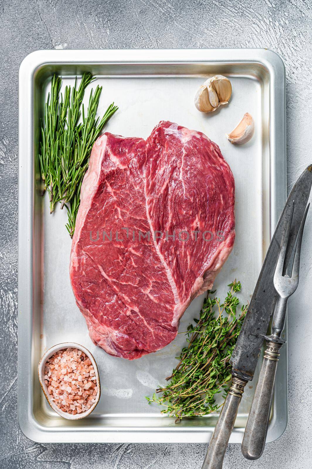 Beef raw steak cut in a baking dish. White background. Top view.