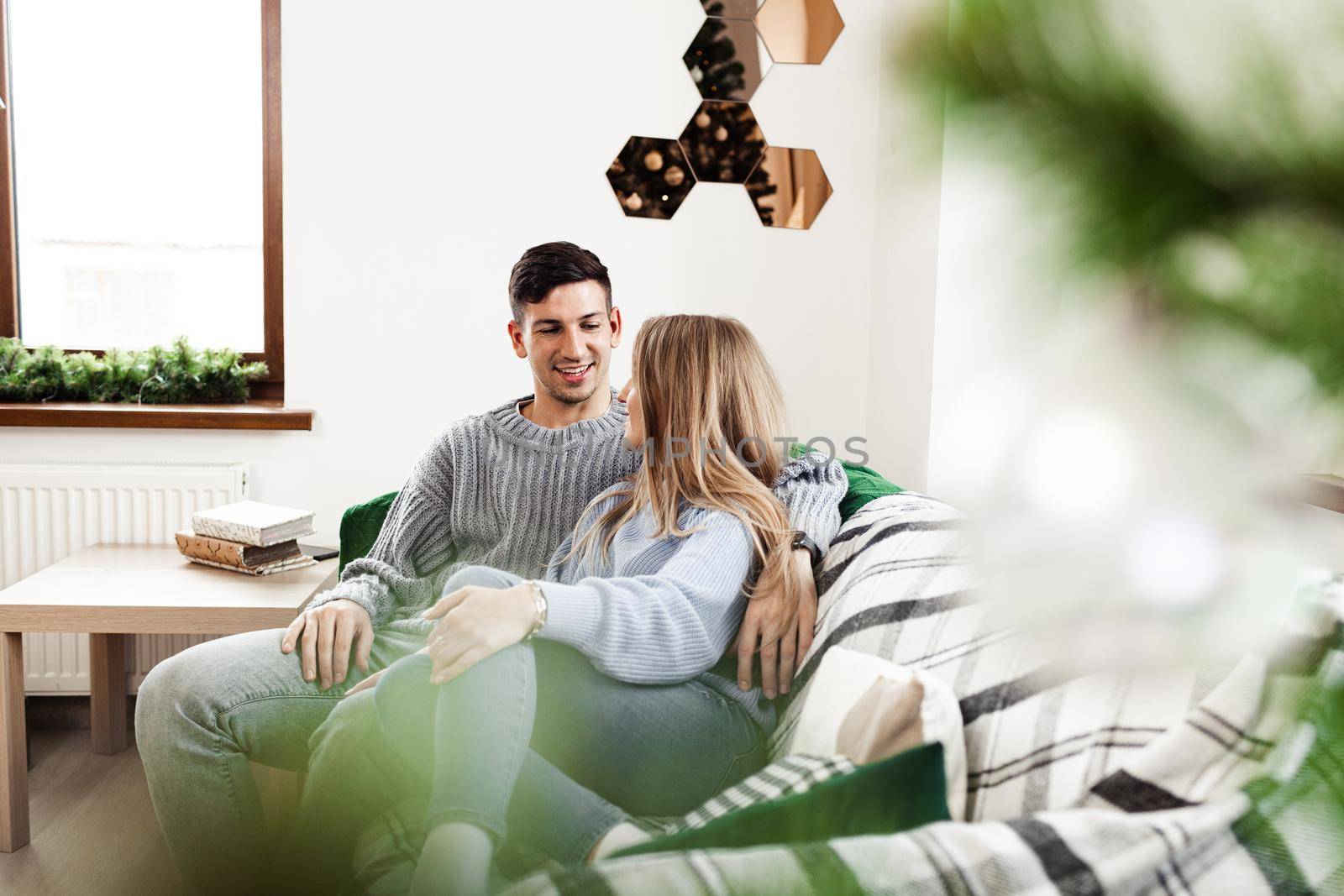 Sweet couple embracing on sofa at home during christmas holidays