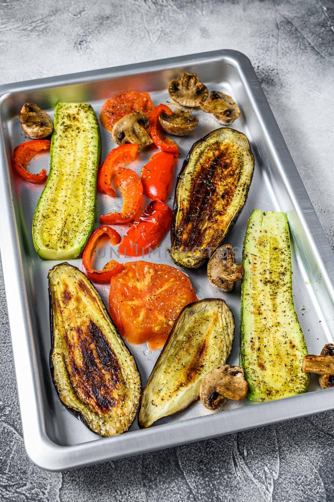 Roasted vegetables on a baking pan. White background. Top view.