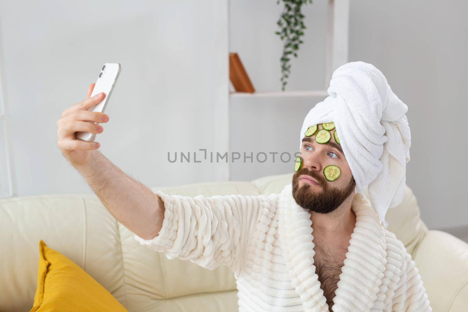 Bearded man holding cucumber slices on the face. Spa at home, body and skin care for male concept