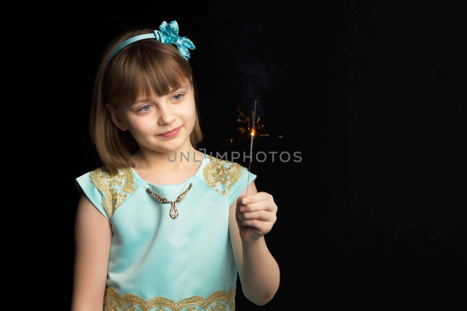 little girl holding firewors on black background