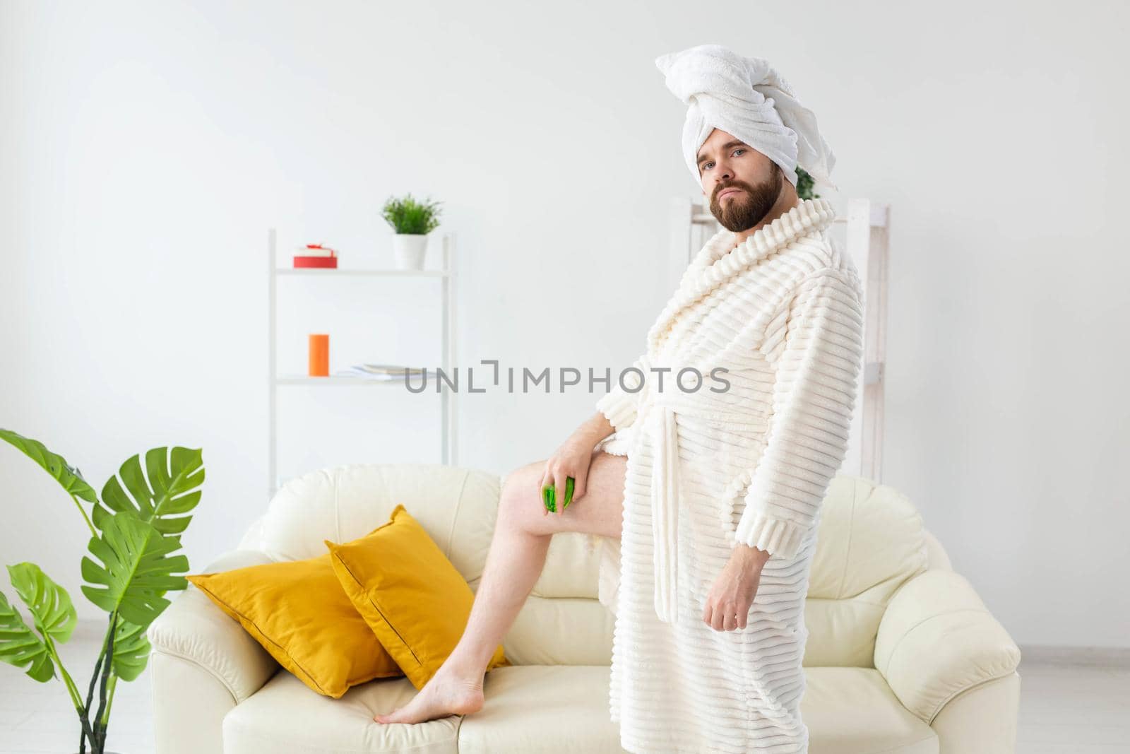 Portrait of cheerful guy wear turban towel makes himself a massage with massage brush. Male skin care and spa concept