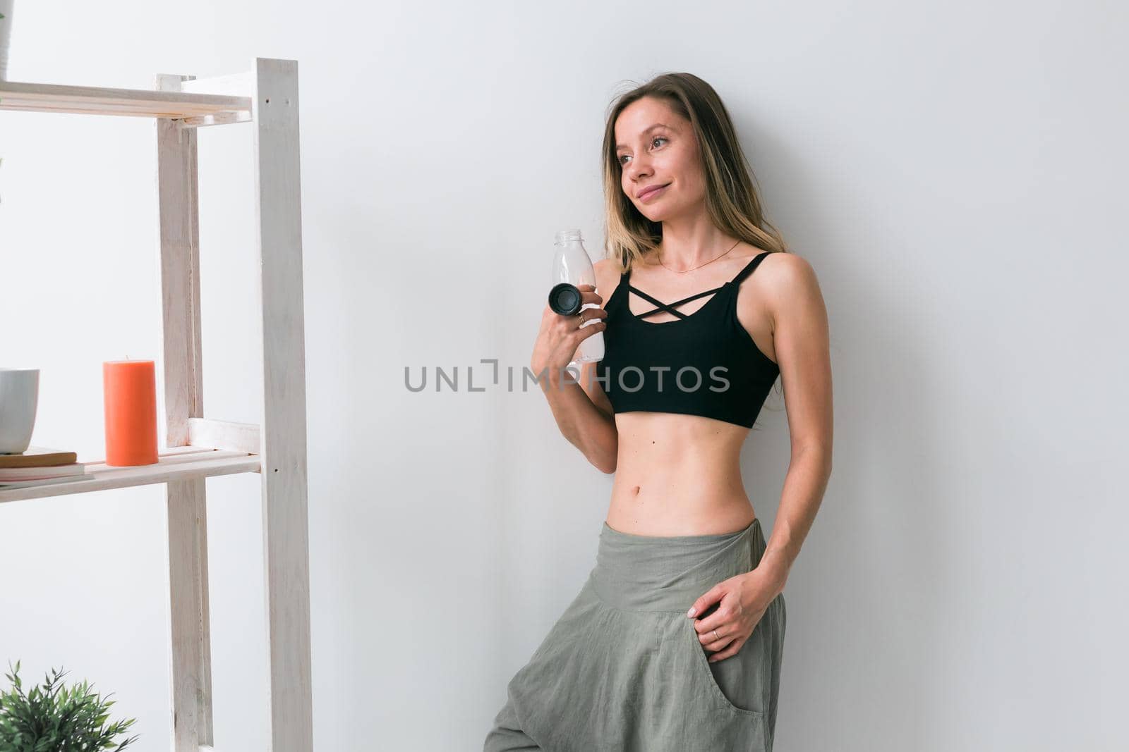 Sporty young woman drinking water after training at home. Active lifestyle and wellness
