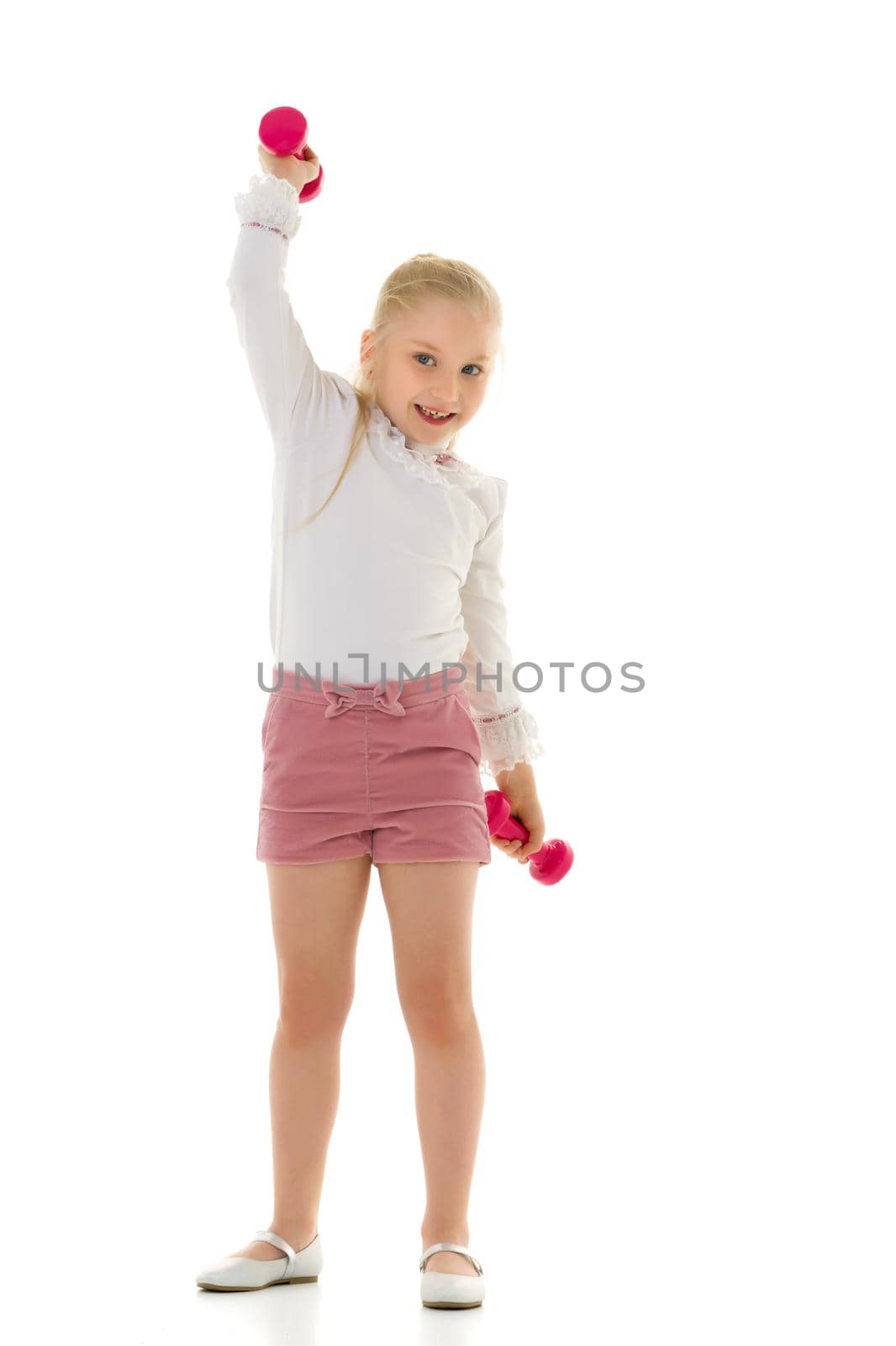 A cute little girl doing exercises with dumbbells. The concept of strength, health and sport. Isolated on white background.