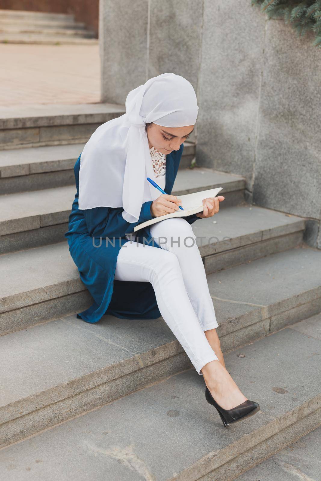 Arab female student sitting on stairs in downtown