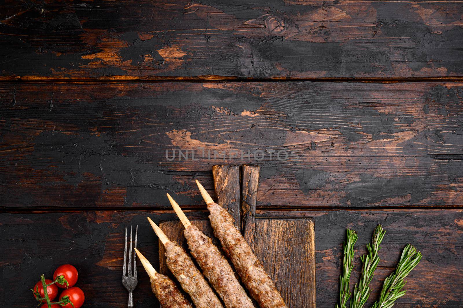 Tikka, shish and kofta kebabs set, on serving board, on old dark wooden table background, top view flat lay, with copy space for text