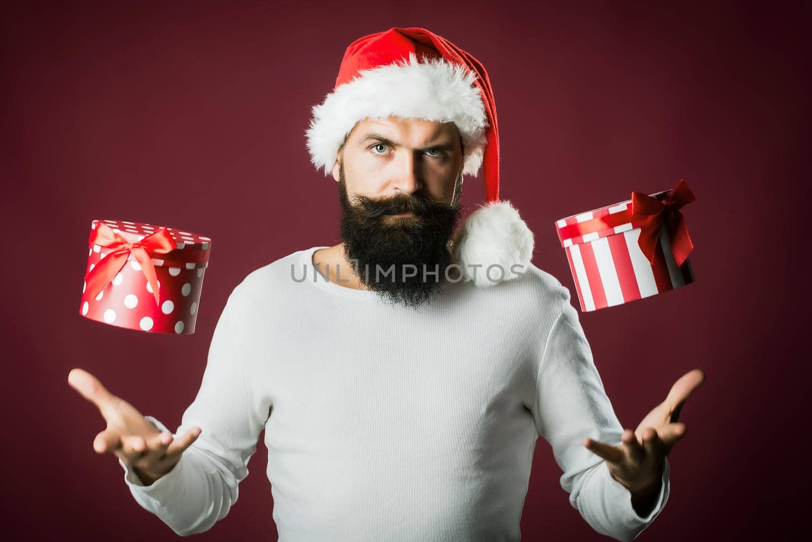 Santa man with beard and moustache holding present gift on red purple background by Tverdokhlib