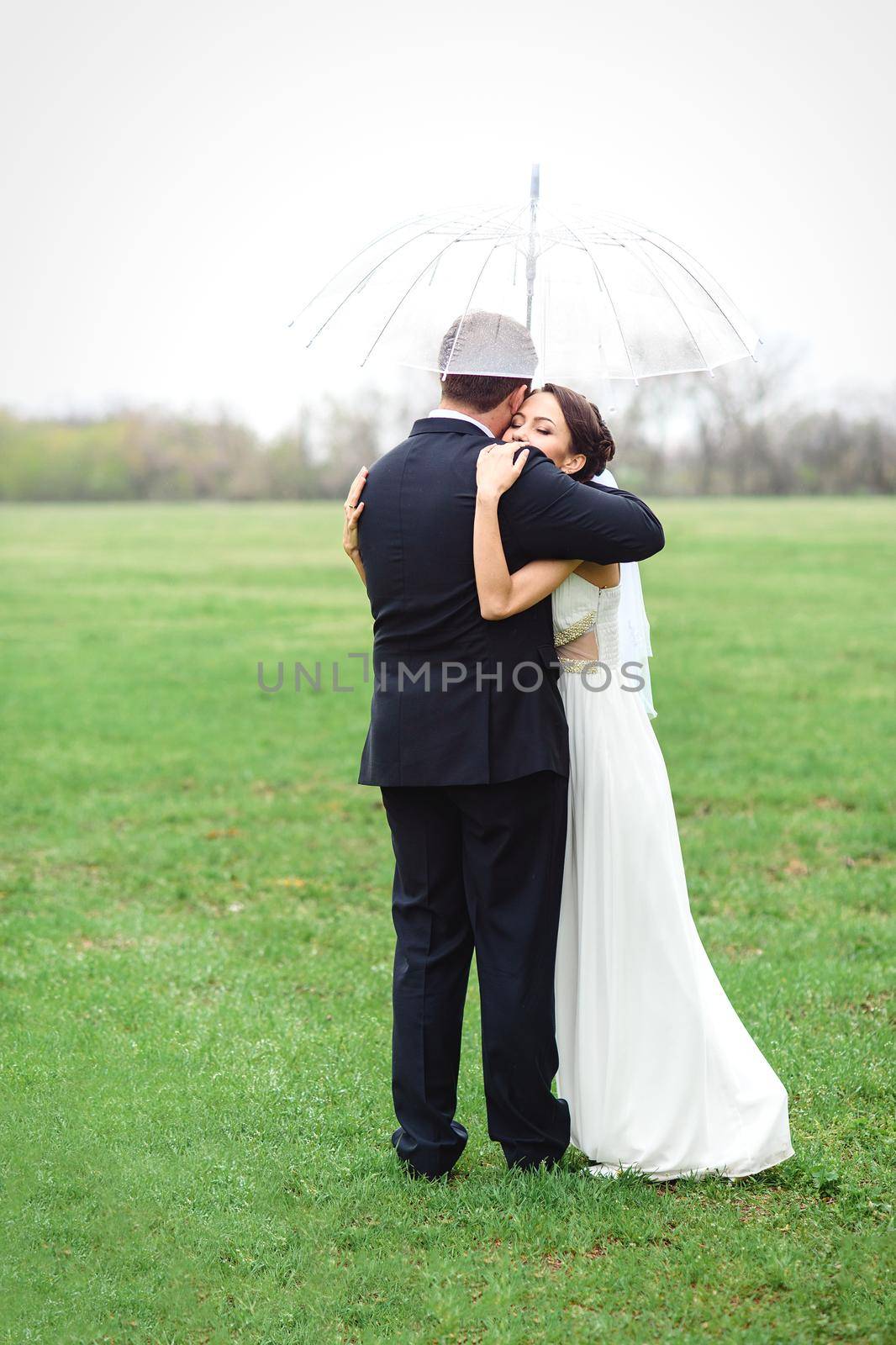 bride and groom on a rainy wedding day walking under an umbrella