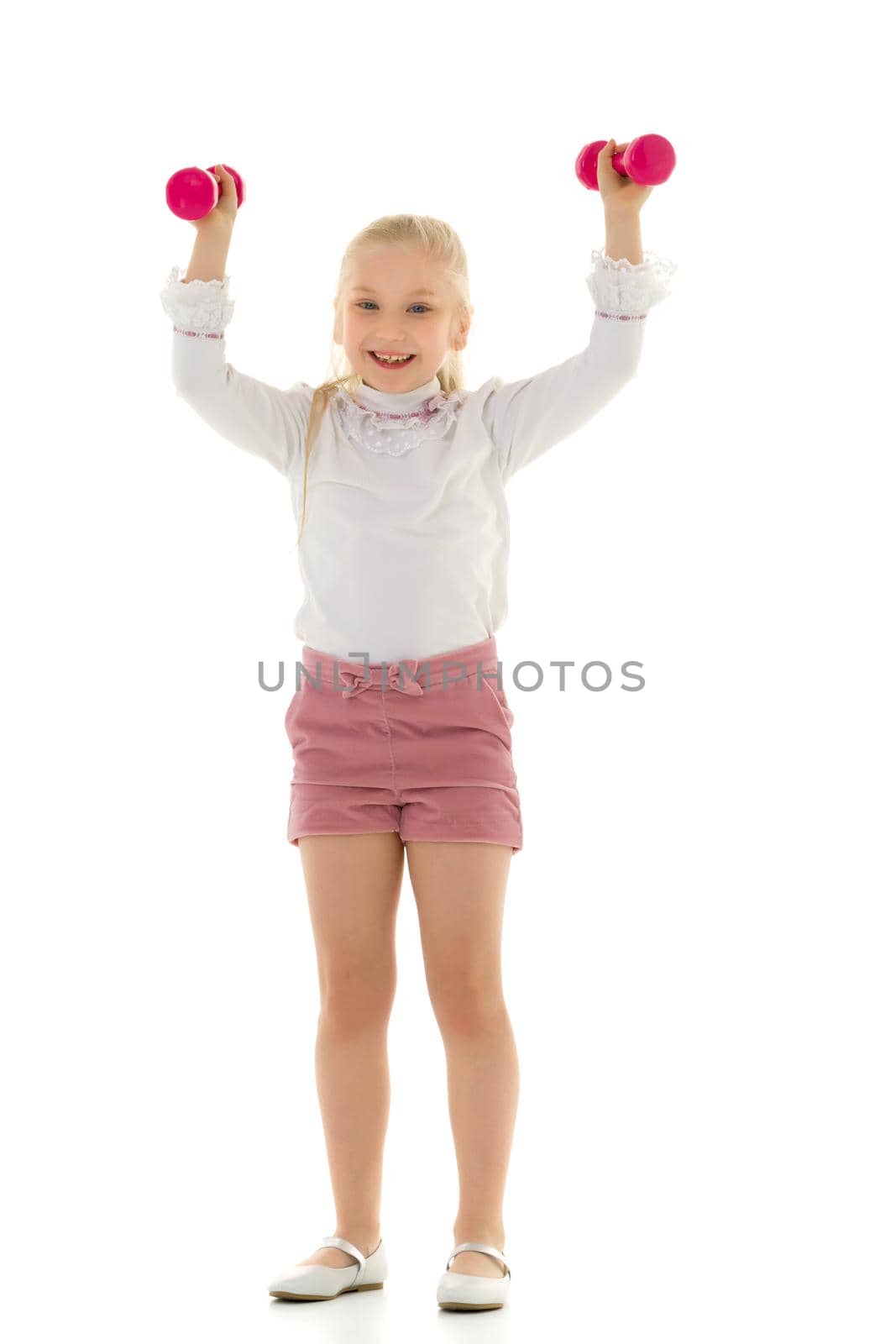 A cute little girl doing exercises with dumbbells. The concept of strength, health and sport. Isolated on white background.