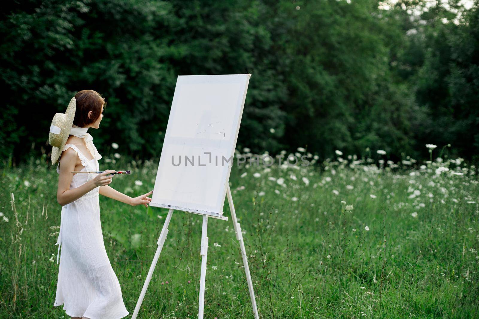 A woman in a white dress in a field with flowers paints a picture by Vichizh
