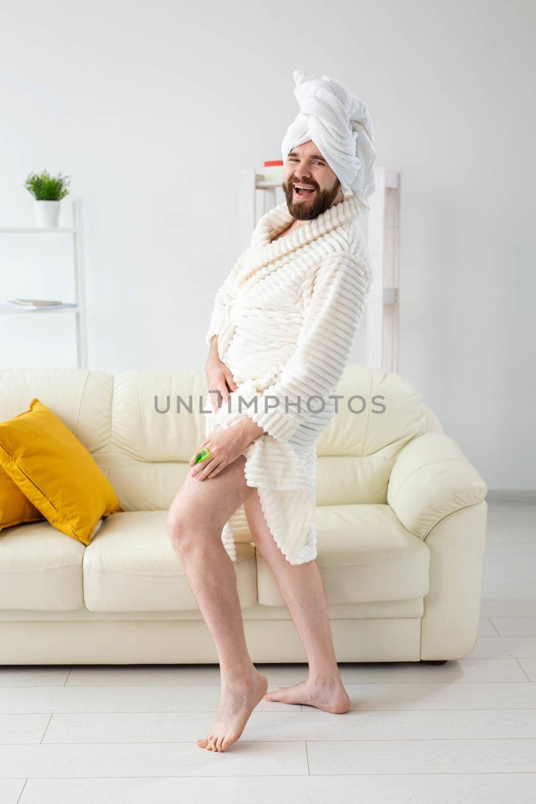 Portrait of cheerful guy wear turban towel makes himself a massage with massage brush. Male skin care and spa concept