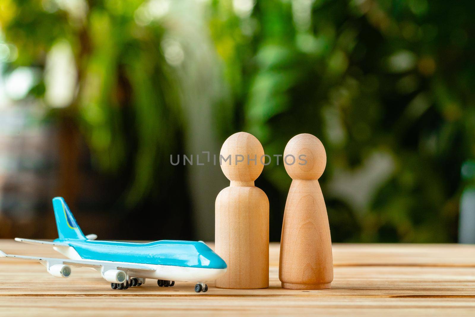 Family travel and vacation concept. Wooden figures of family and toy plane by Fabrikasimf