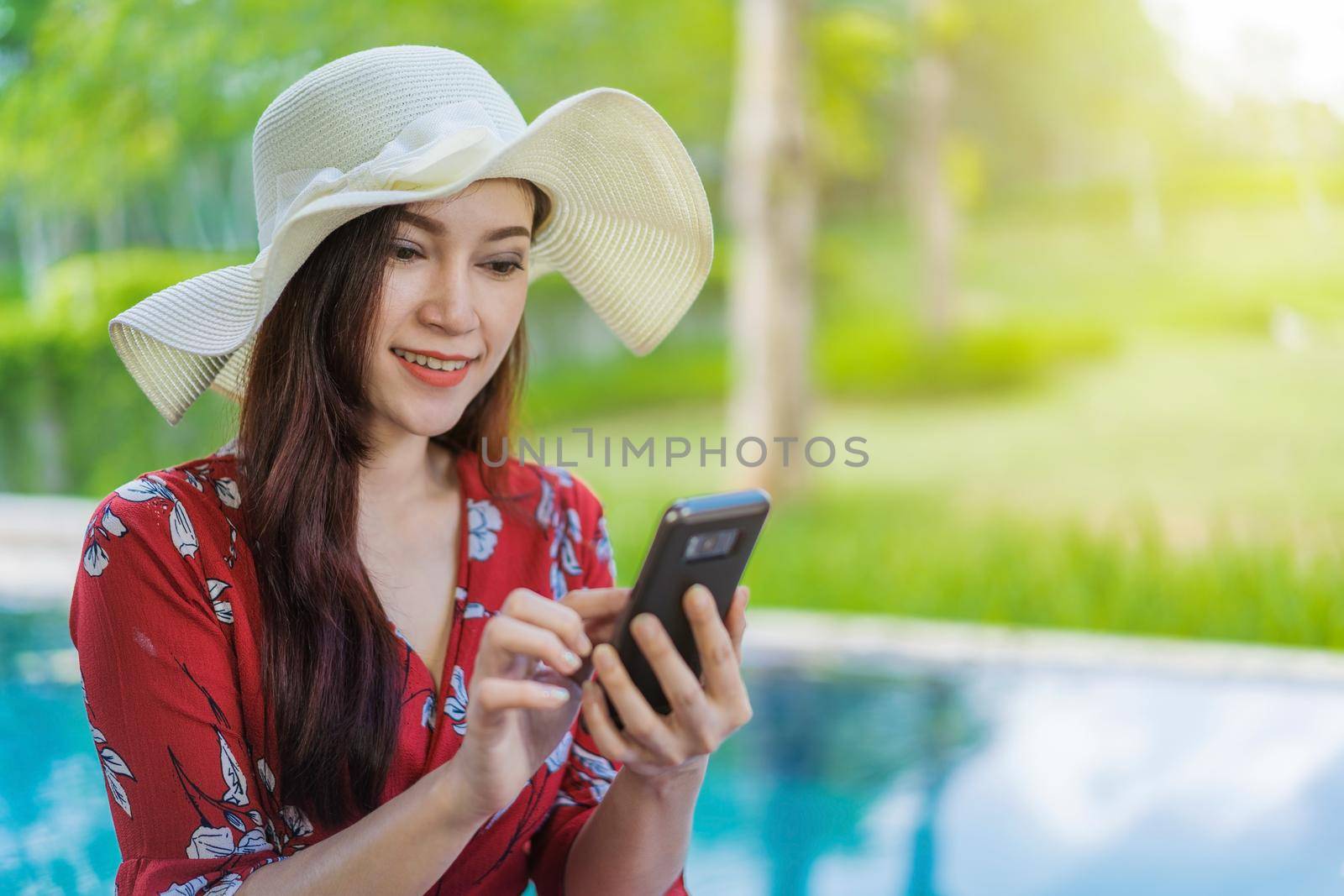 woman using smartpone in swimming pool by geargodz