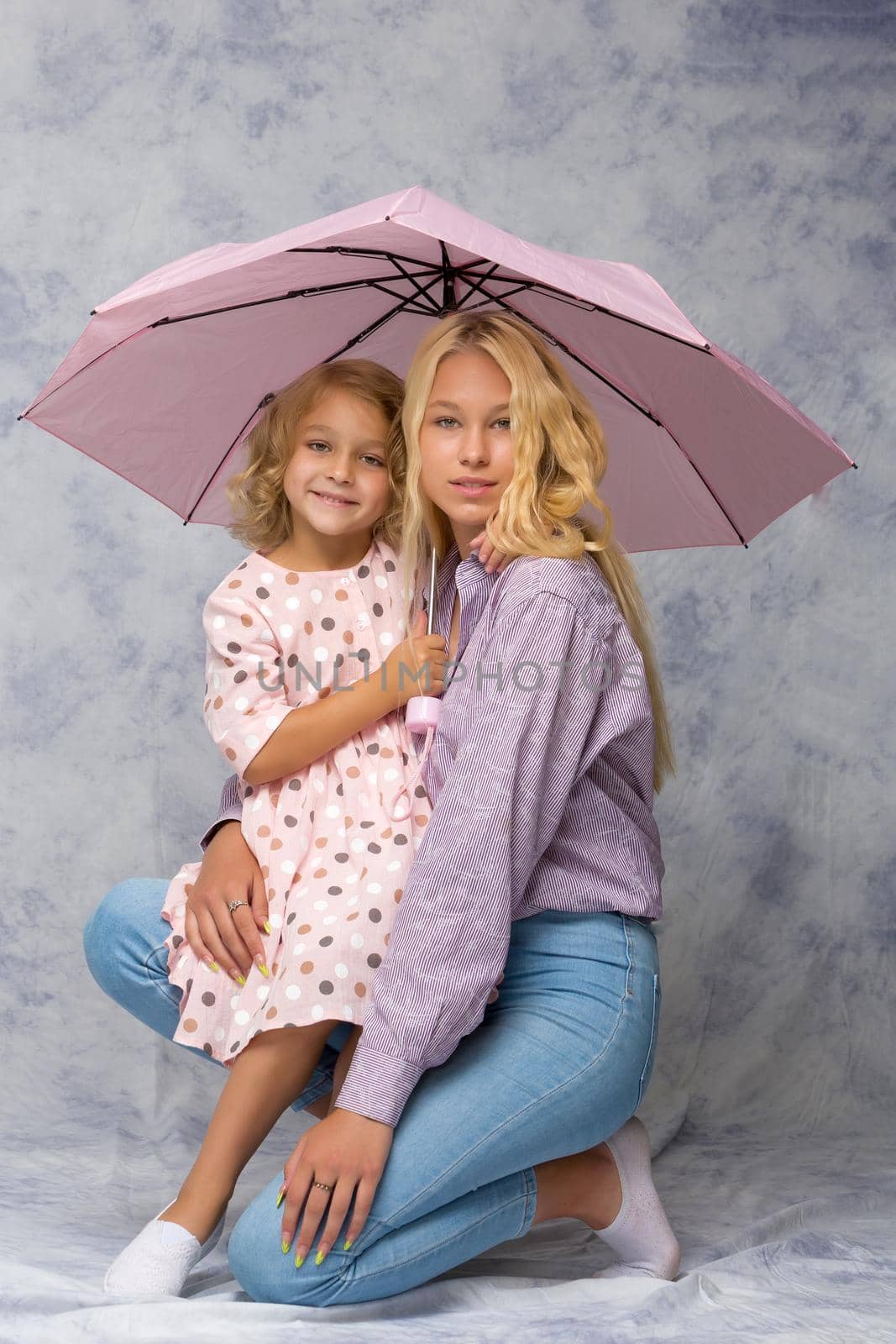 Beautiful young girl hugging her little sister. The concept of a happy childhood, family values.