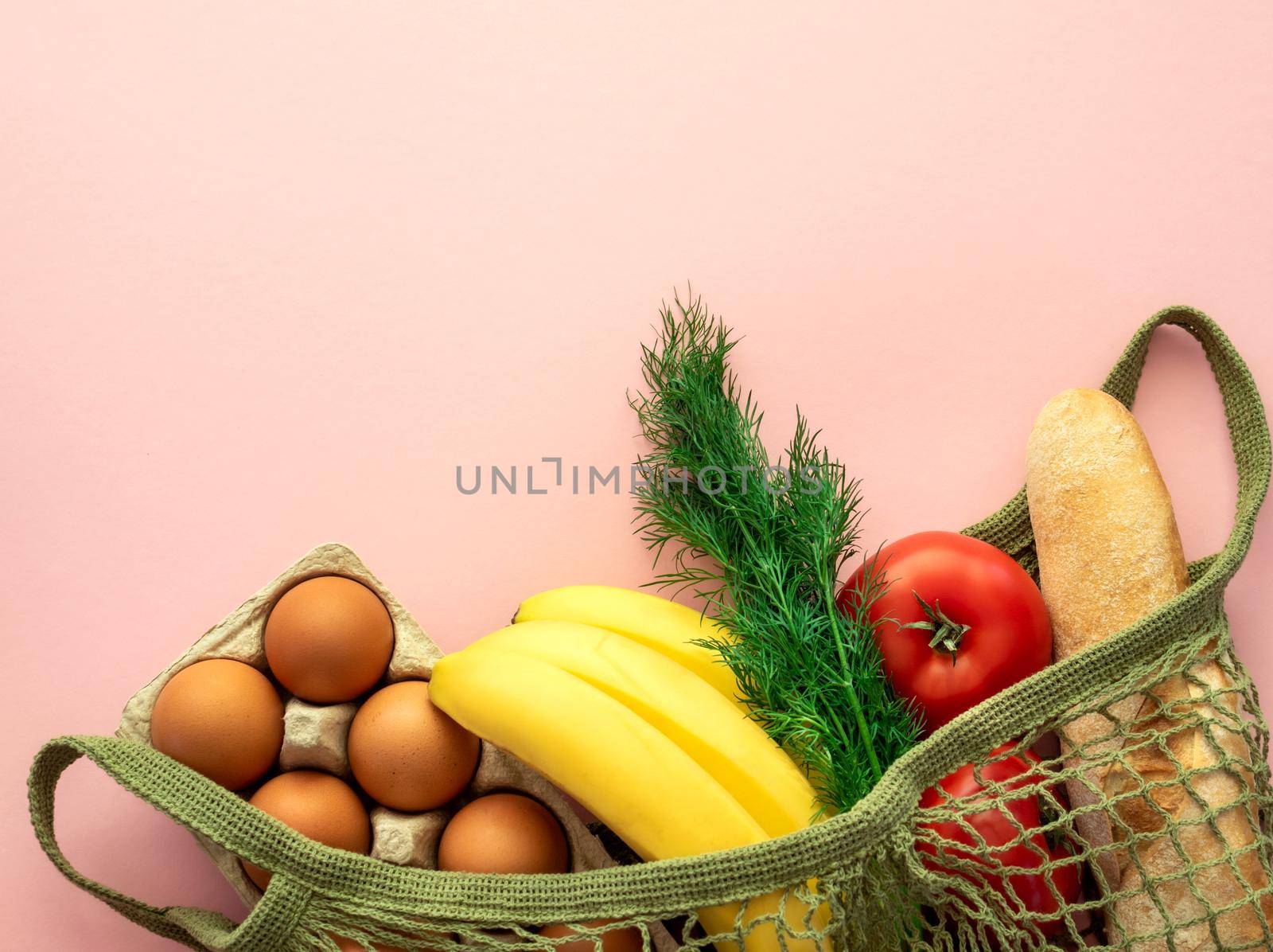 Eco concept - life without plastic. Zero waste concept. Package-free food shopping. Cotton mesh bag with products on pink background. Food delivery, donation, coronavirus, humanitarian assistance.
