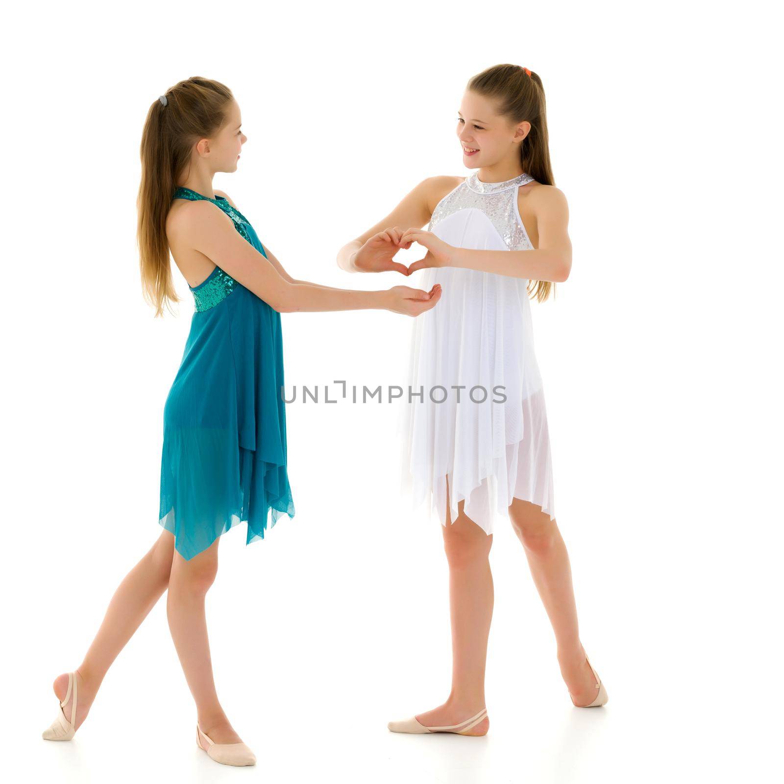 Two adorable girls gymnasts folded hands in the form of a heart. Sign of love. Isolated on a white background.