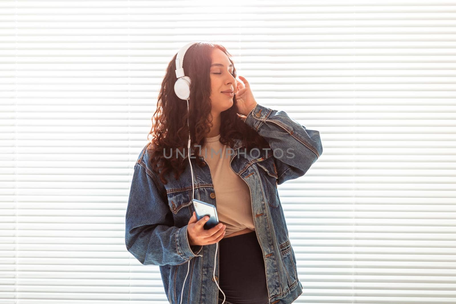 Young peaceful pregnant woman listens to pleasant classical music using smartphone and headphones. Concept of positive attitude before childbirth