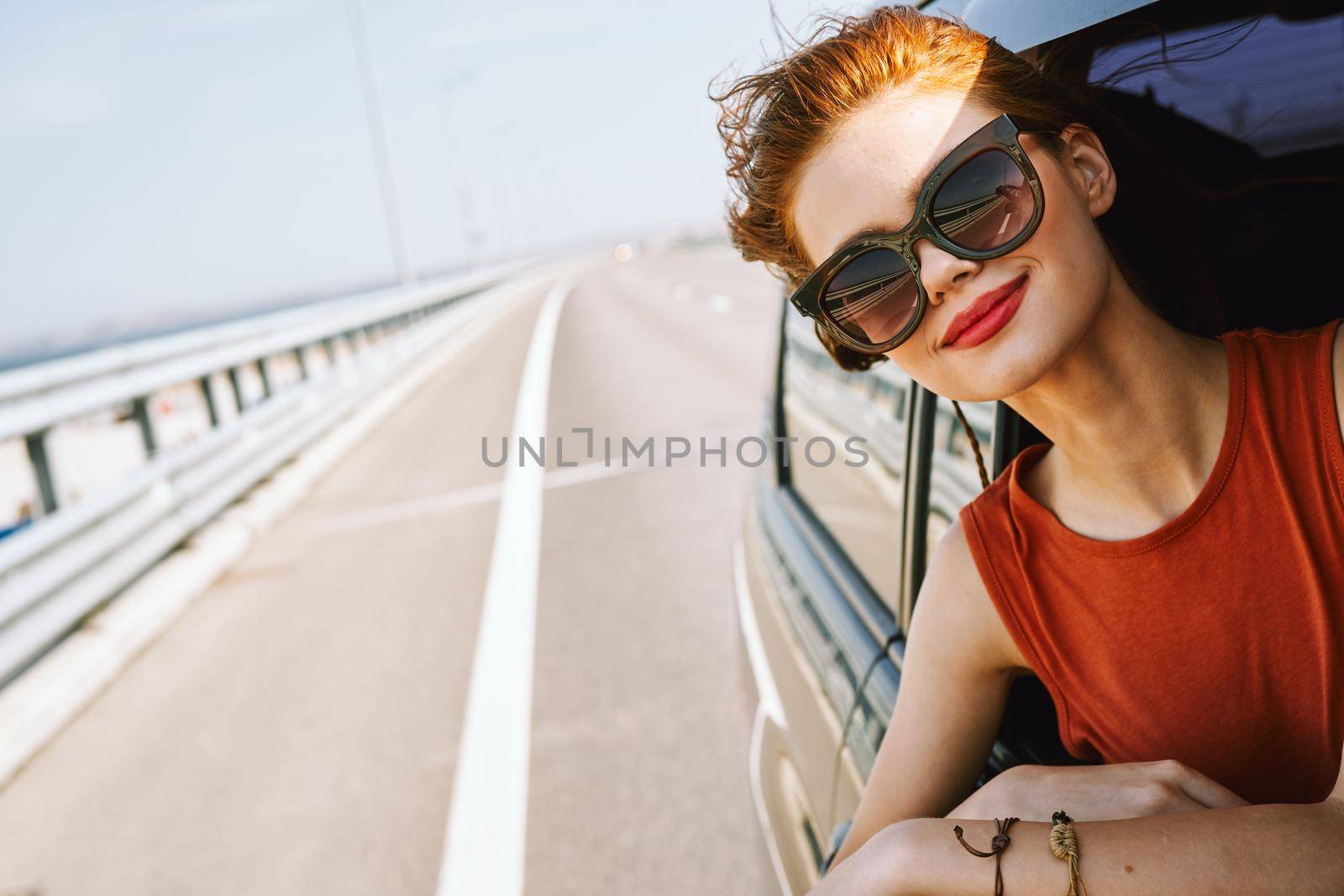 cheerful woman peeking out of the car window trip adventure lifestyle. High quality photo