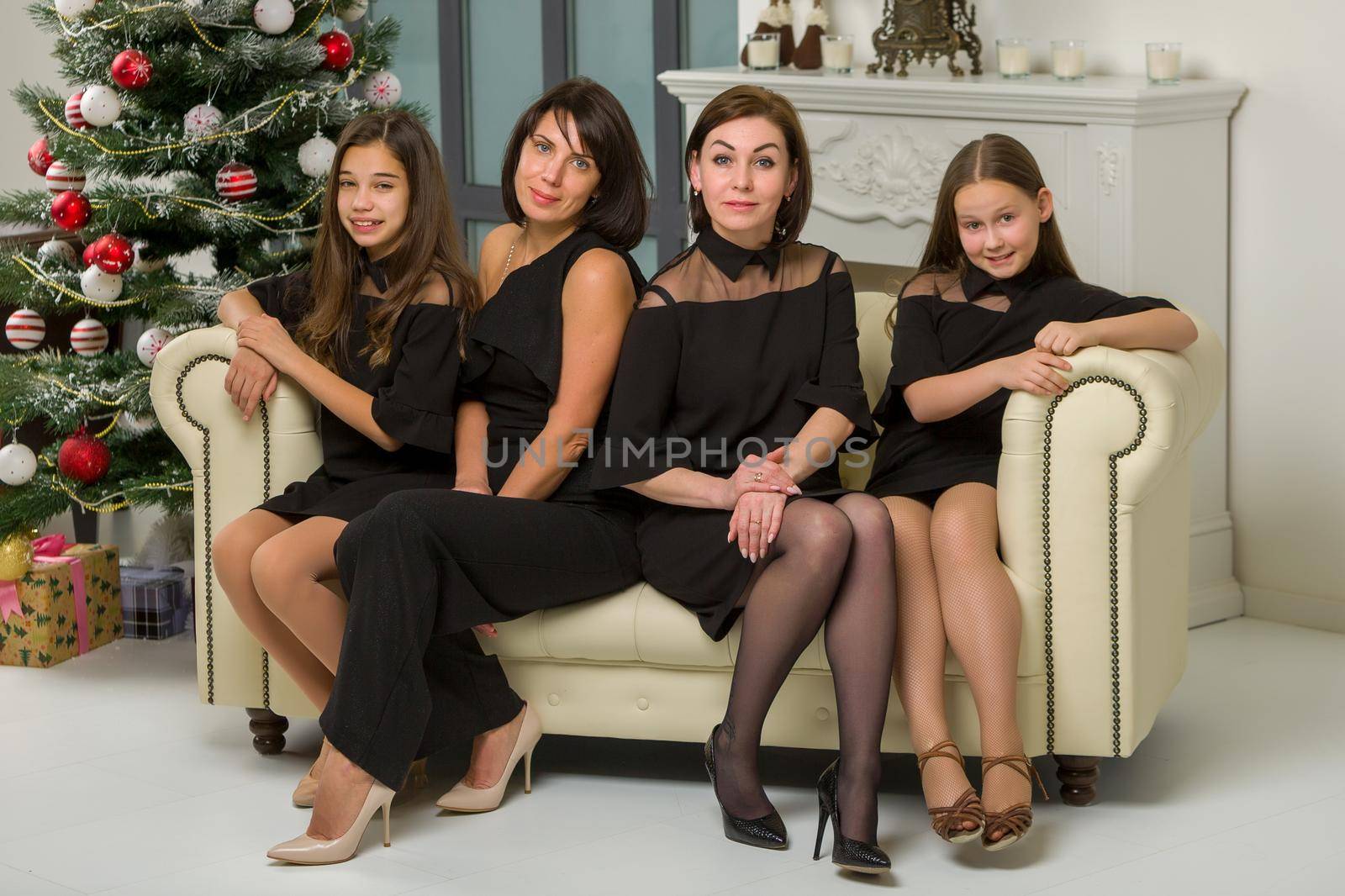 Young mothers with children near the fireplace and the Christmas tree on the eve of the holidays. The concept of family well-being.
