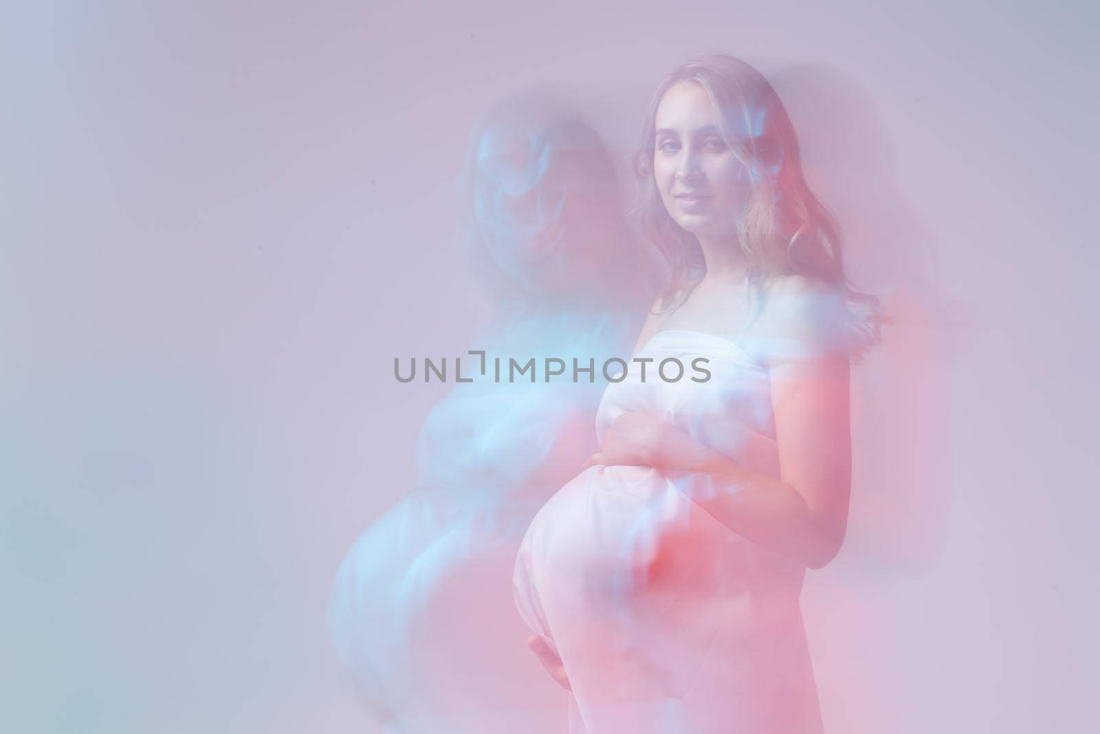 Elegant pregnant young woman standing wearing light fabric. Pregnancy, fantasy and fairy tale.
