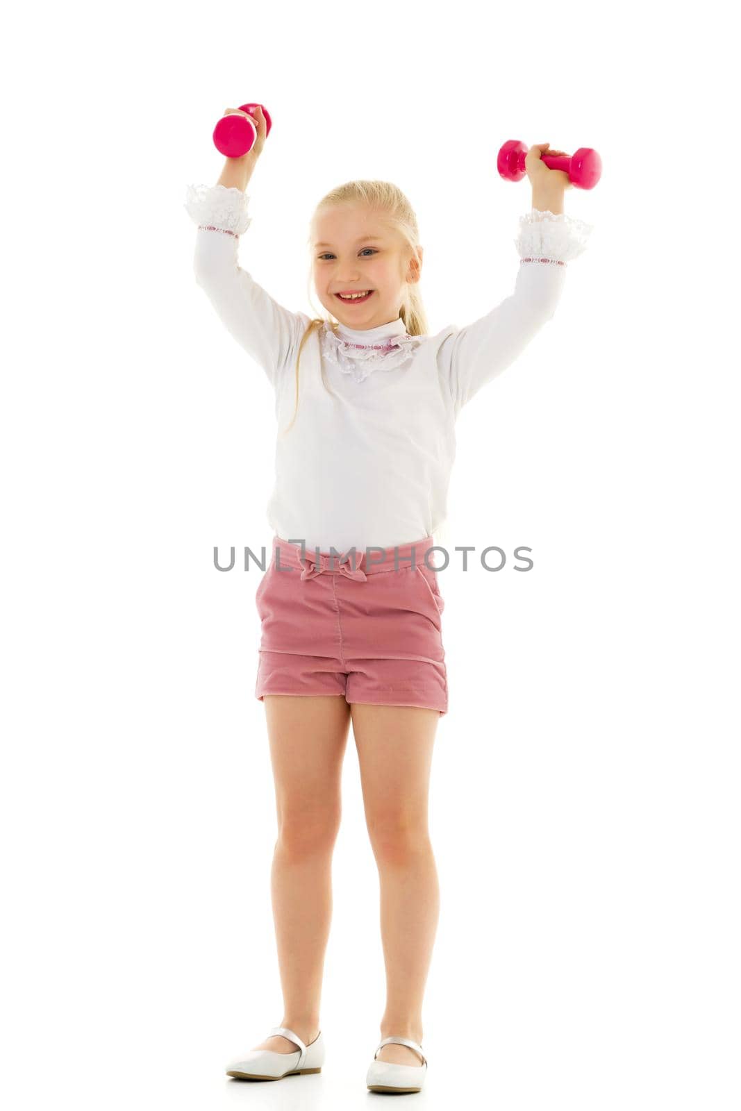 A cute little girl doing exercises with dumbbells. The concept of strength, health and sport. Isolated on white background.