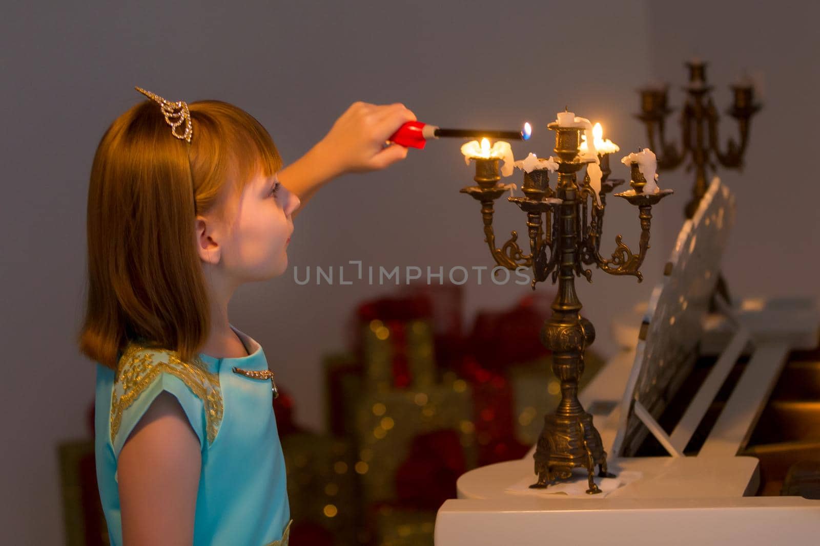 Romantic little girl lights candles on Christmas night. Family holidays concept.