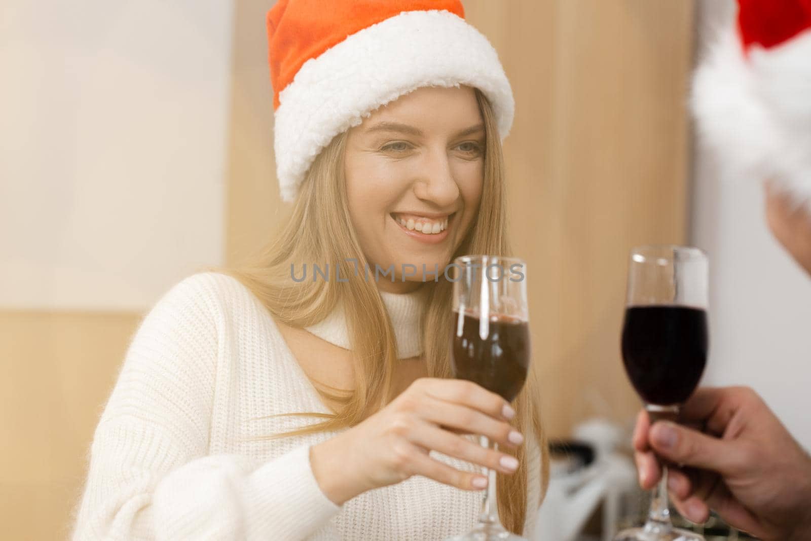 Young couple in Santa hats drinking wine and celebrating Christmas, close up