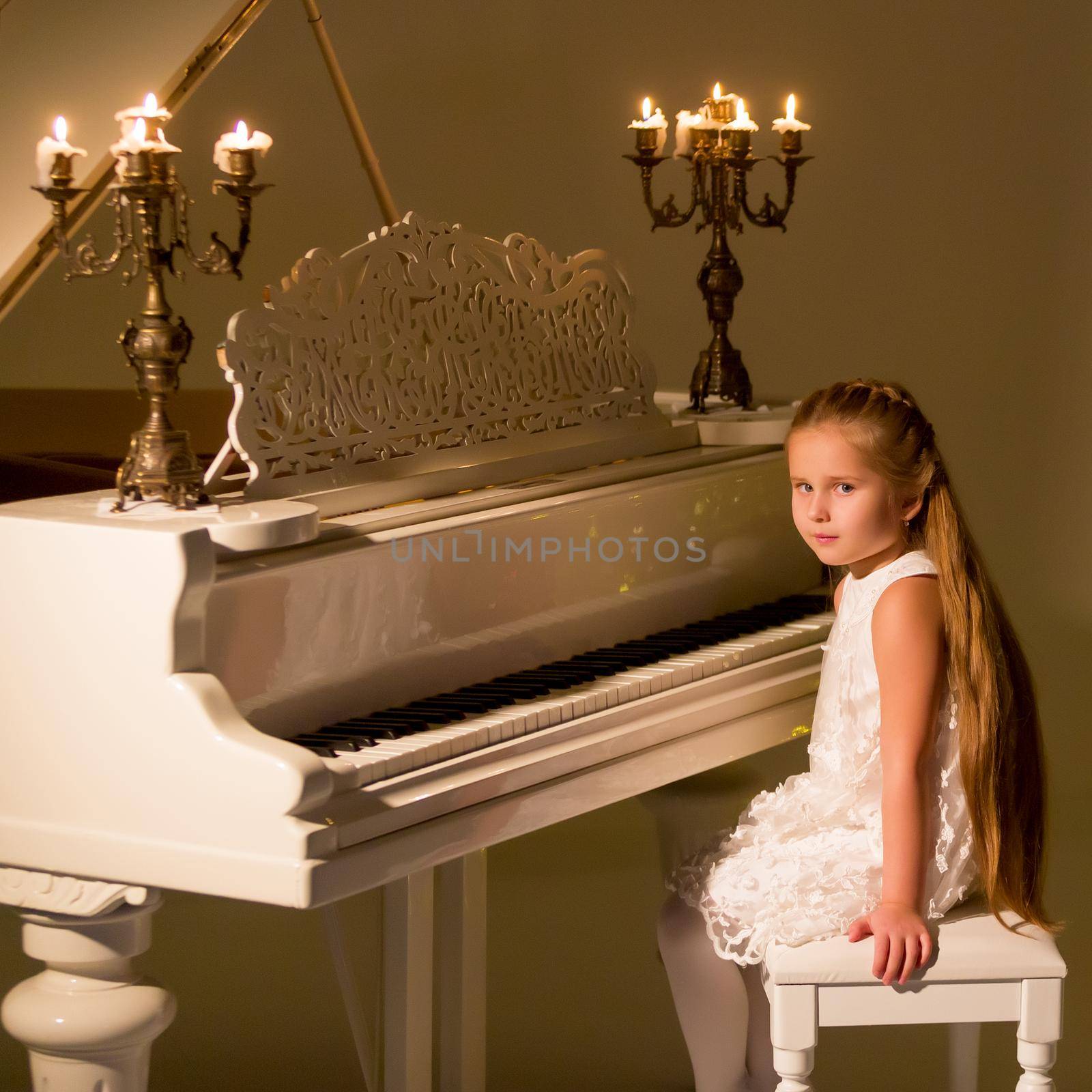 Little girl plays the piano by candlelight. by kolesnikov_studio
