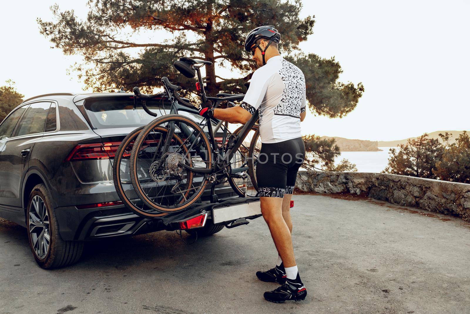 Male cyclist loading his bicycle on a rack of his crossover car after a ride