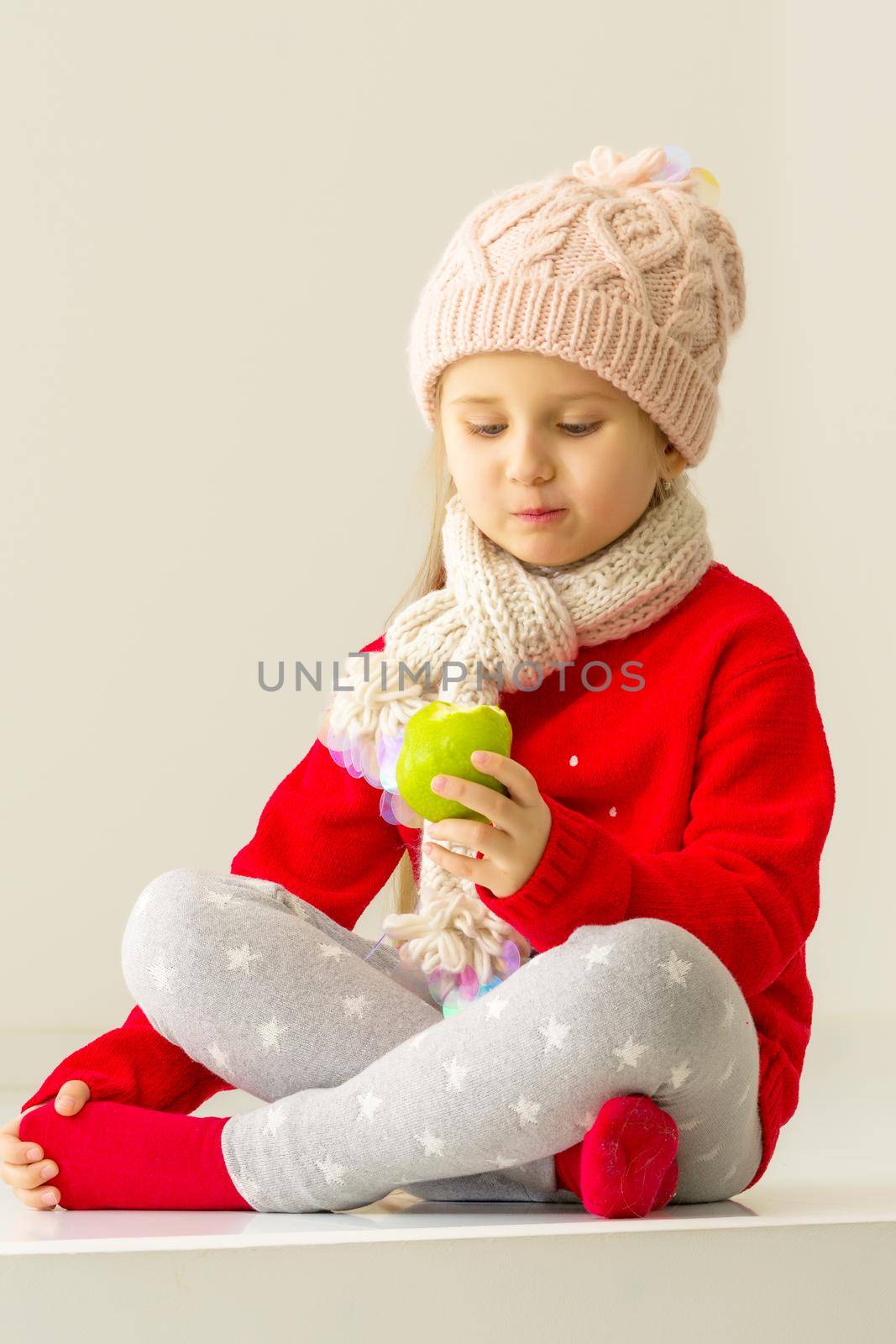 Cute little girl eating an apple. Healthy food concept. On a white background.