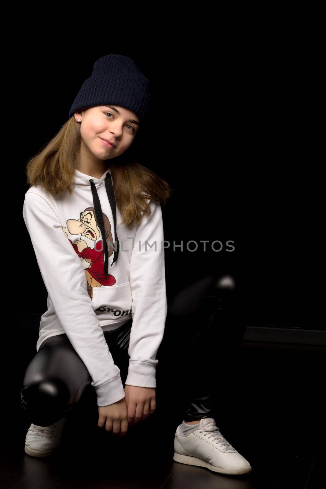 The concept of youth sports and clothes.Beautiful little teenager girl in a sports youth suit. On a black background.