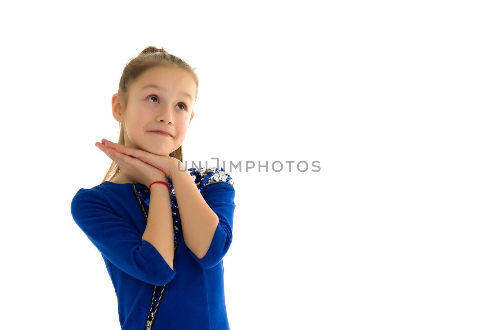 A charming little girl folded her hands around her face. The concept of beauty and fashion, children's emotions. Isolated on white background.
