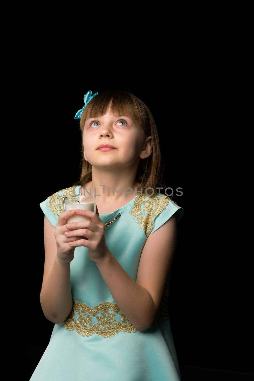 A cute little girl is looking up. The concept of emotions, happy childhood. Isolated on a black background.