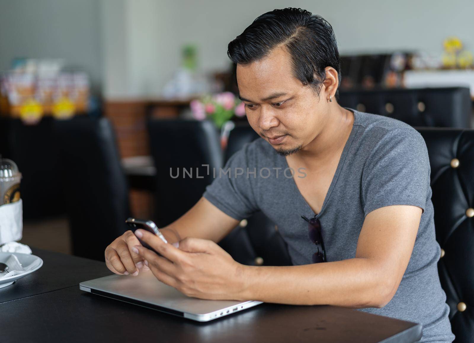 man using smartphone in a cafe by geargodz