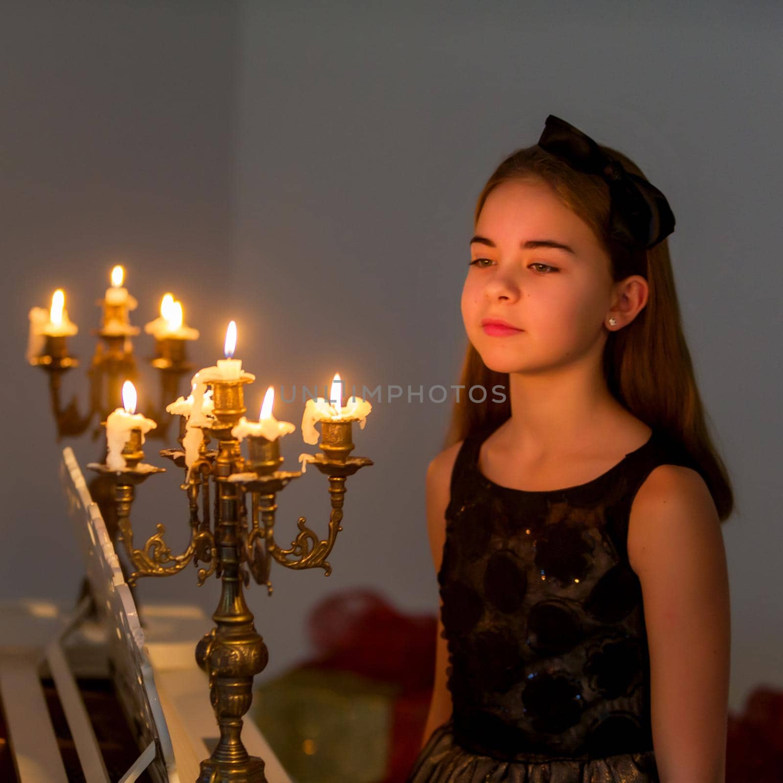 A little girl in a dark room by candlelight. by kolesnikov_studio