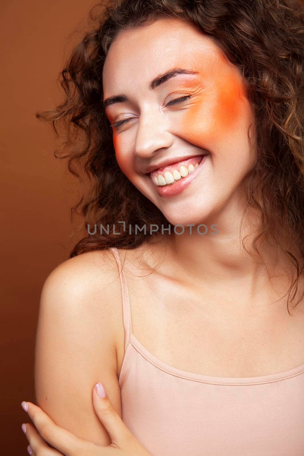 young pretty girl with curly hair posing cheerful on brown background, lifestyle people concept by JordanJ