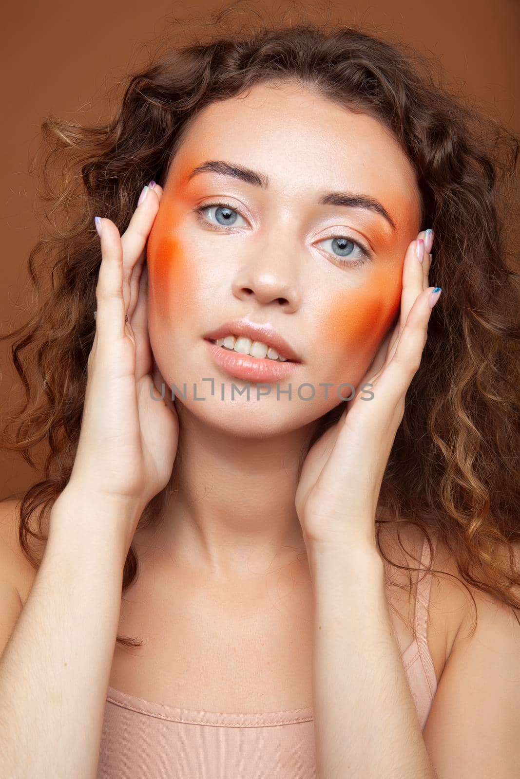 young pretty girl with curly hair posing cheerful on brown background, lifestyle people concept closeup