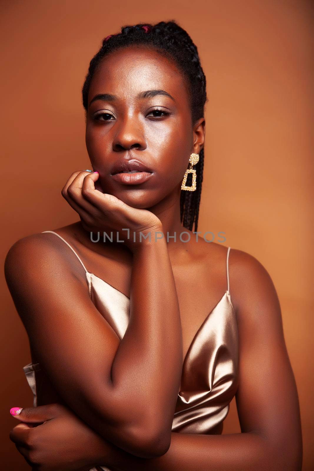 pretty young african american woman with braids posing cheerful gesturing on brown background, lifestyle people concept closeup