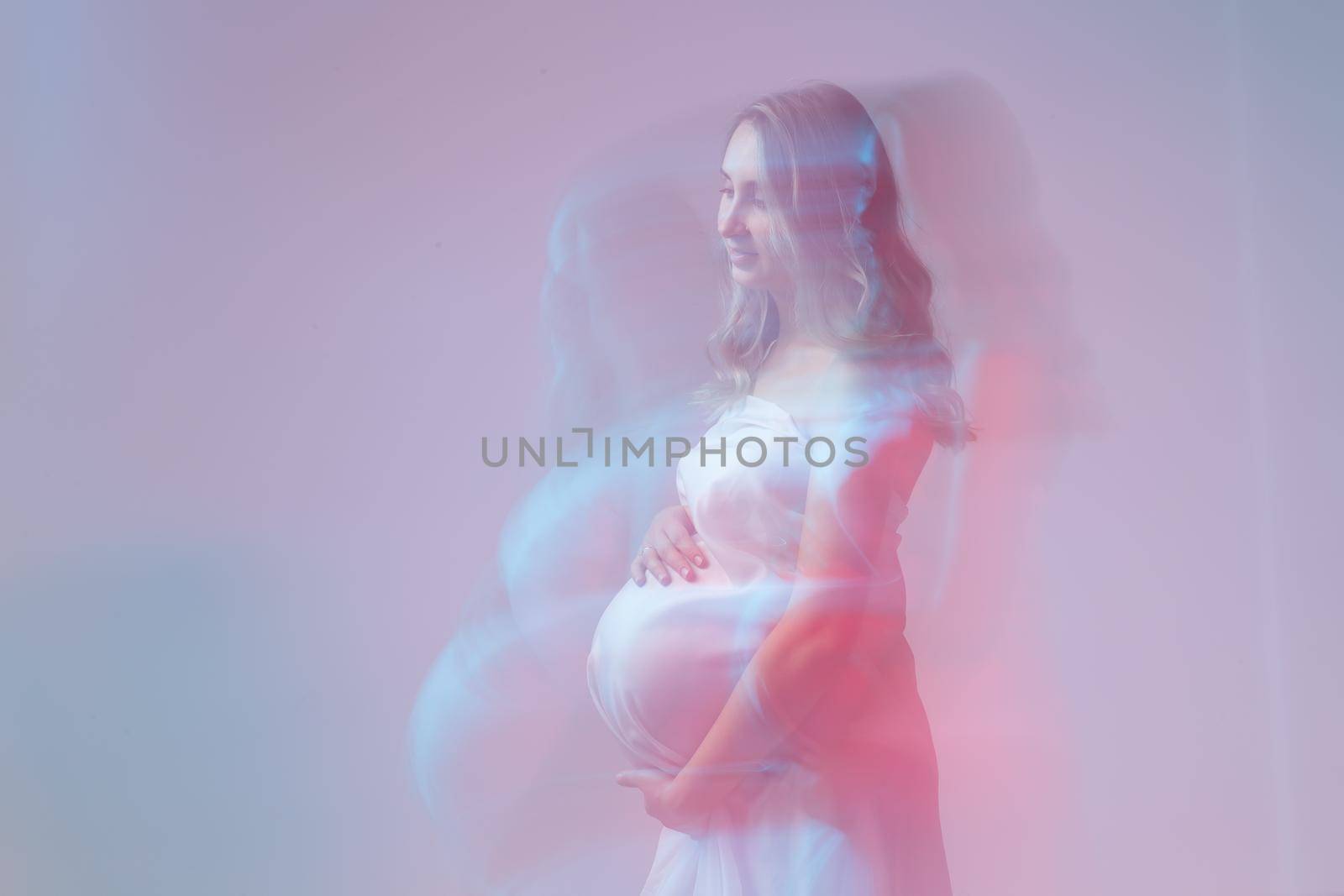 Elegant pregnant young woman standing wearing light fabric. Pregnancy, fantasy and fairy tale.