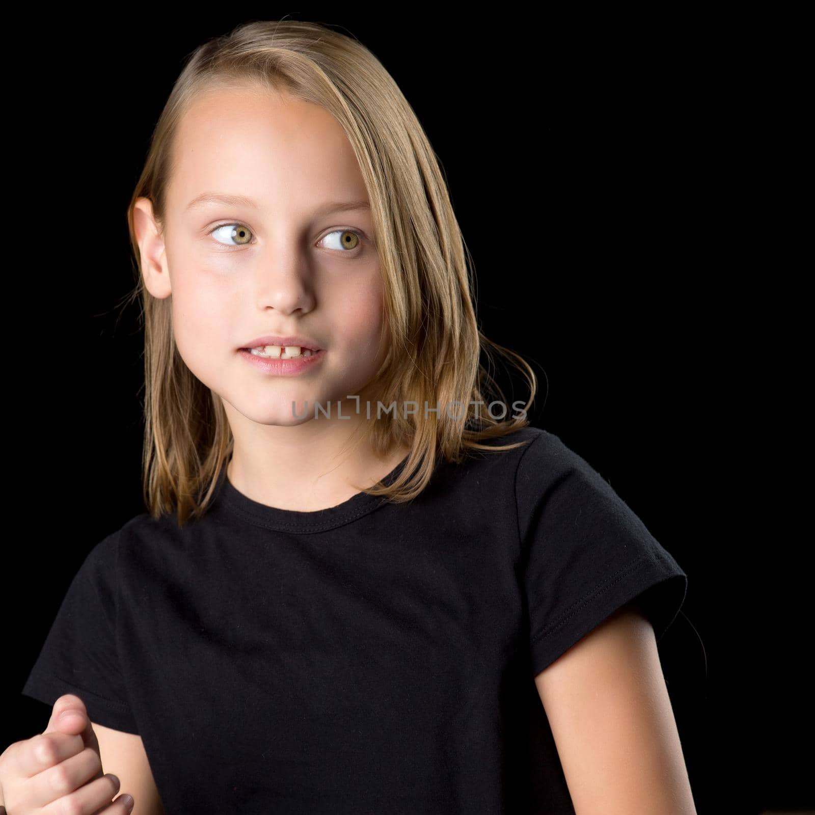 Beautiful girl posing in the studio. Close up portrait of beautiful blonde teenage girl in black t-shirt gesturing against black background.