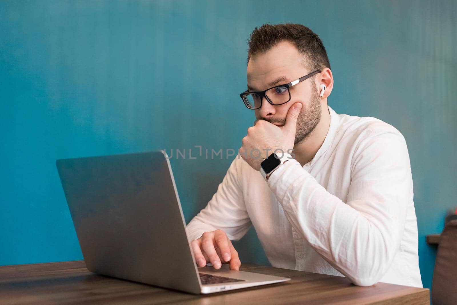 Attractive guy young European businessman works in a laptop sitting at a table in a cafe.