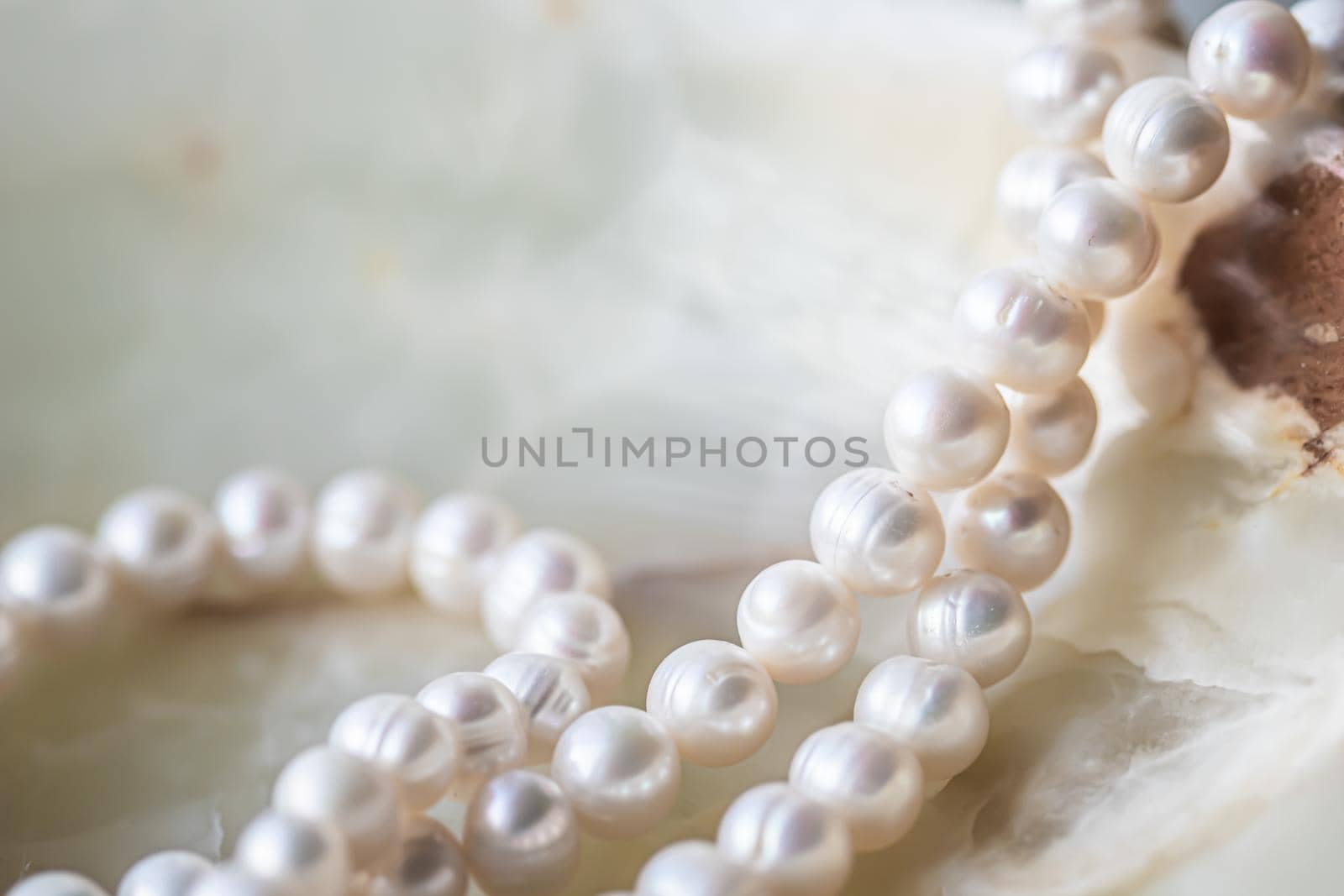 Nature white string of pearls on marble background in soft focus, with highlights by Olayola